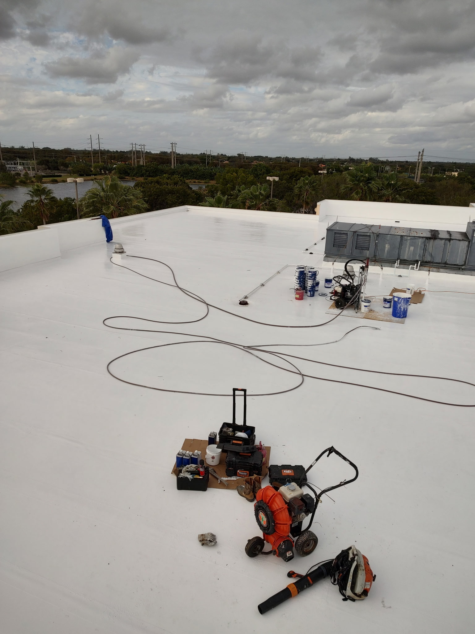 Roof coating application in progress with equipment